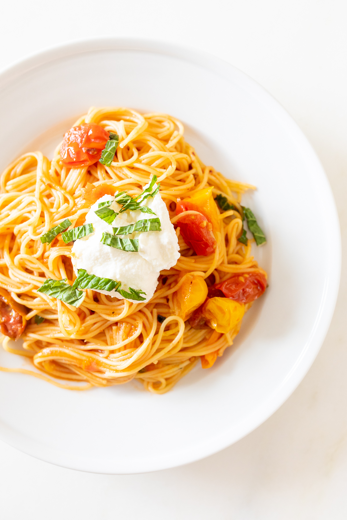 A white plate full of cherry tomato pasta.