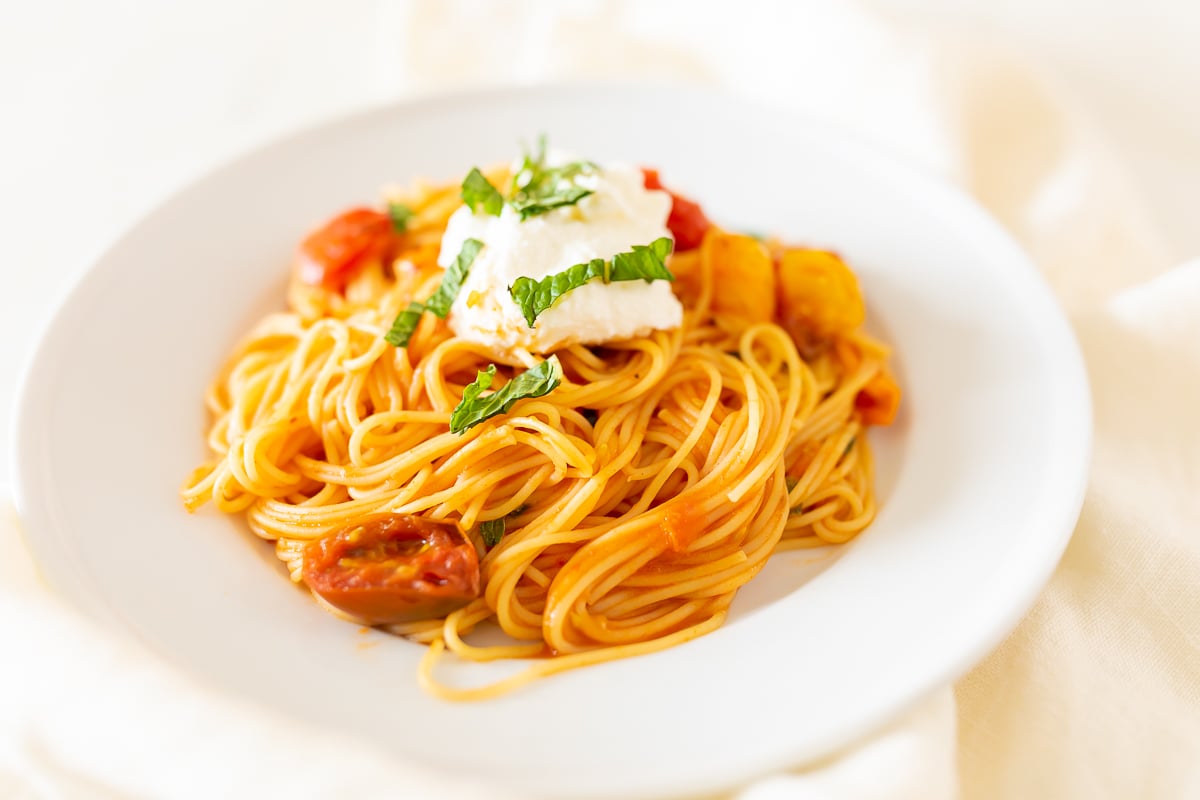 A white plate full of cherry tomato pasta.