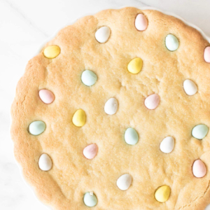An Easter cookie cake with Cadbury eggs, baked in a white tart pan.