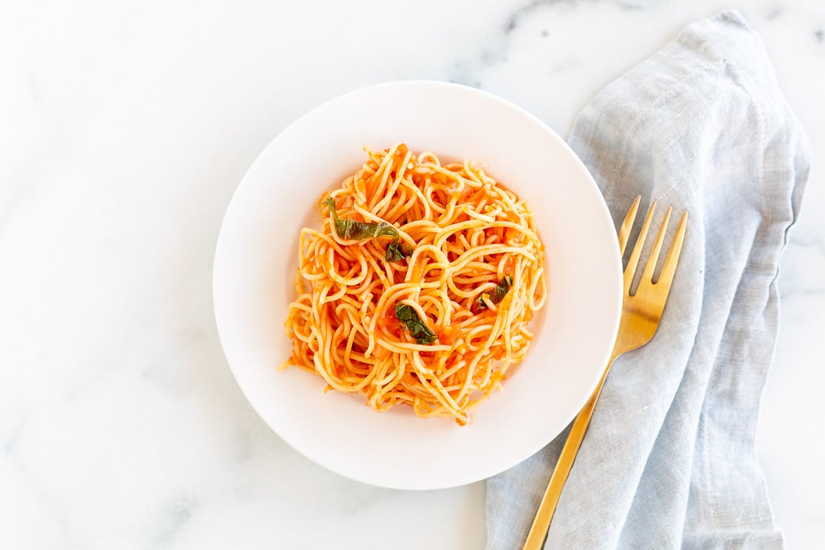 A white plate of pasta with pomodoro sauce. 