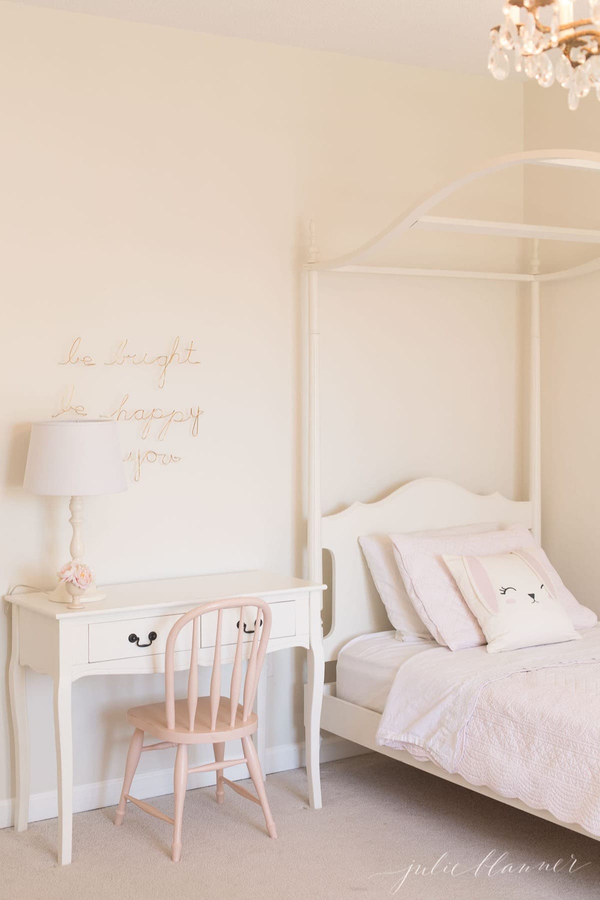 A white girls' bedroom and canopy bed with a bedside table painted with furniture paint.