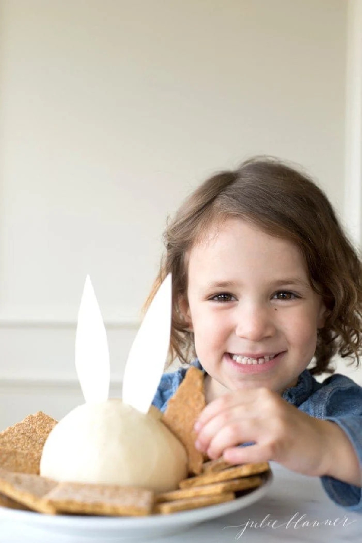 A little girl using a graham cracker to dip into an Easter bunny cheese ball.