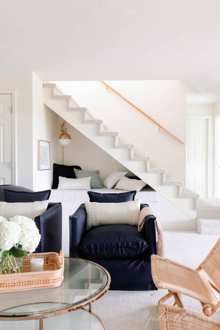 glass coffee table navy chairs and stair nook behind