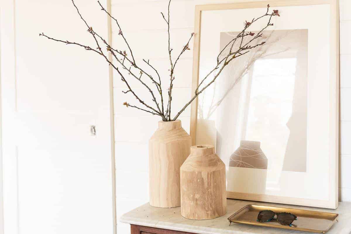 Wood vases on a vintage table in a white mudroom.