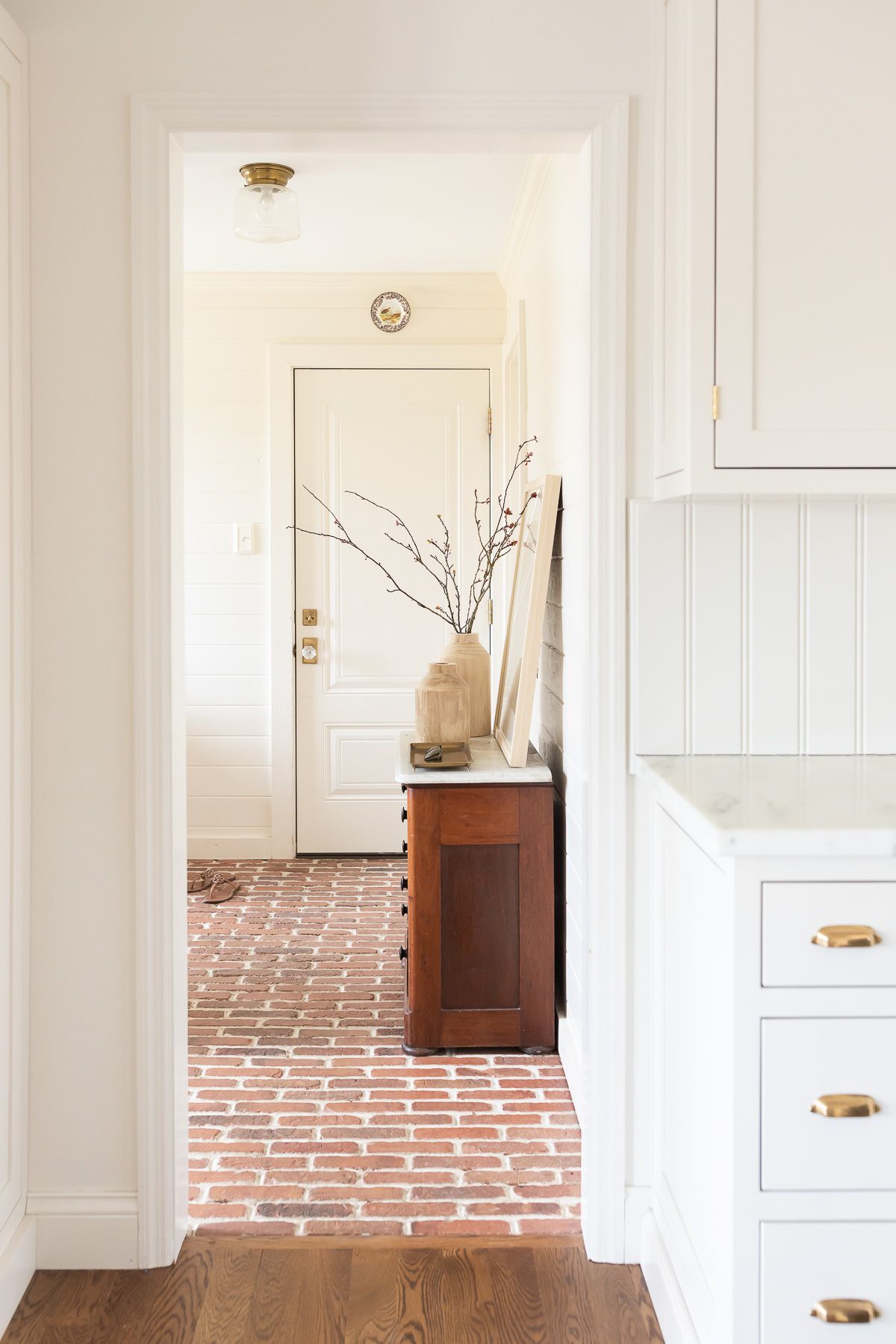 Wood vases on a vintage table in a white mudroom.