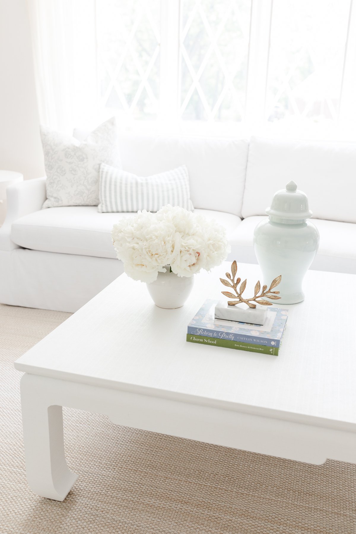 A white living room with an arrangement of white Trader Joe's flowers in a vase on the coffee table.