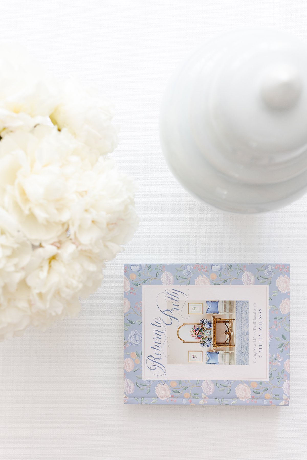 A white living room with an arrangement of white Trader Joe's flowers in a vase on the coffee table.