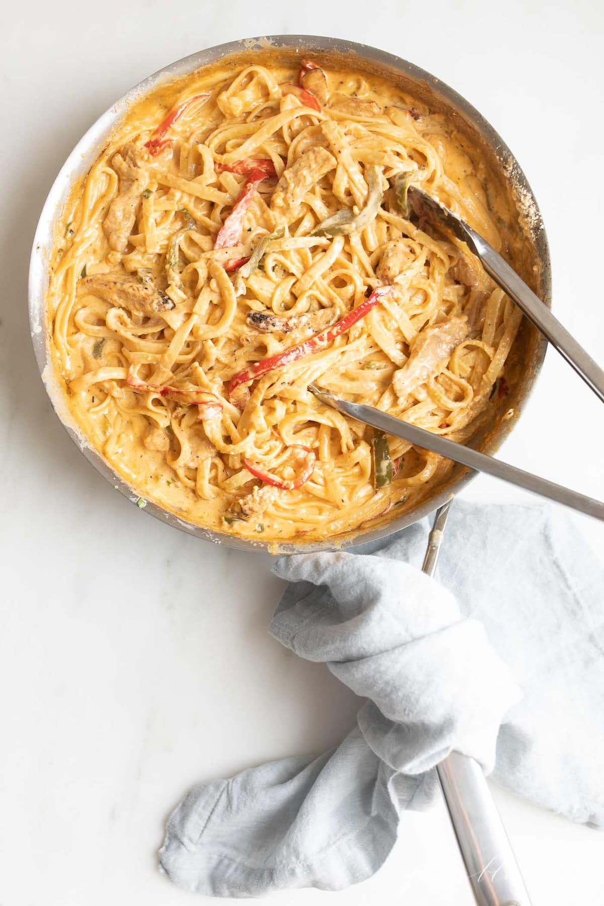 pasta with cajun sauce in skillet with tongs