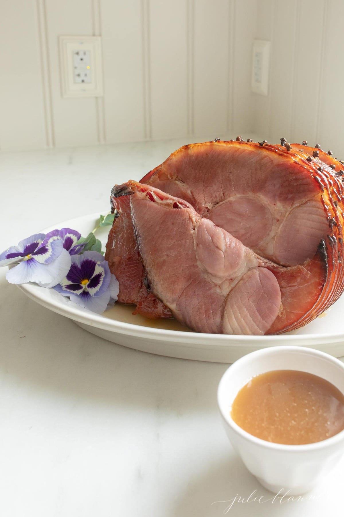 Ham on a white platter, garnished and sliced
