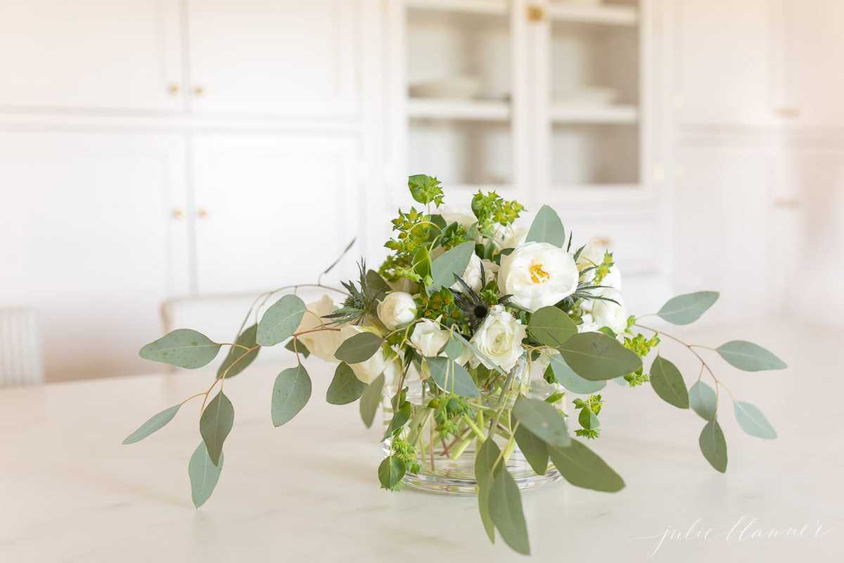 White Ranunculus Centerpiece in glass vase in a white kitchen