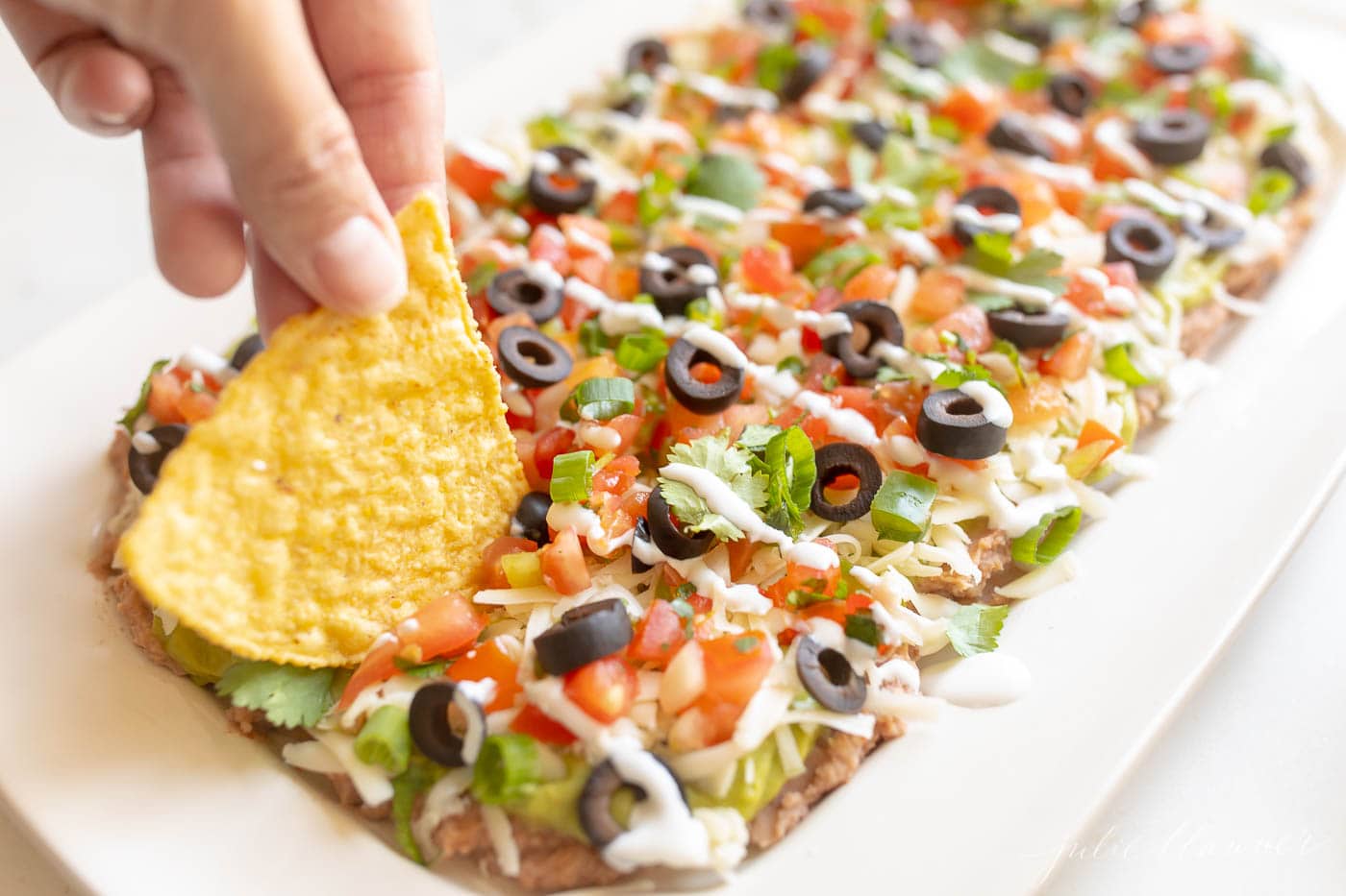 7 layer dip with refried beans, guacamole, pico de gallo, cilantro, green onions, olives and cheese.