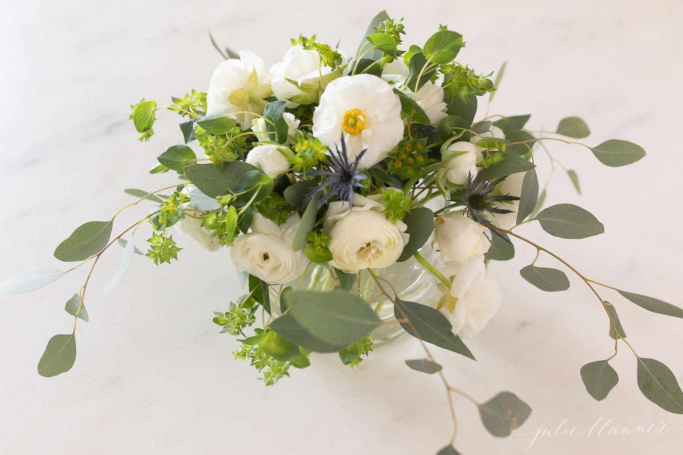 White Ranunulus Centerpiece on a white marble surface.