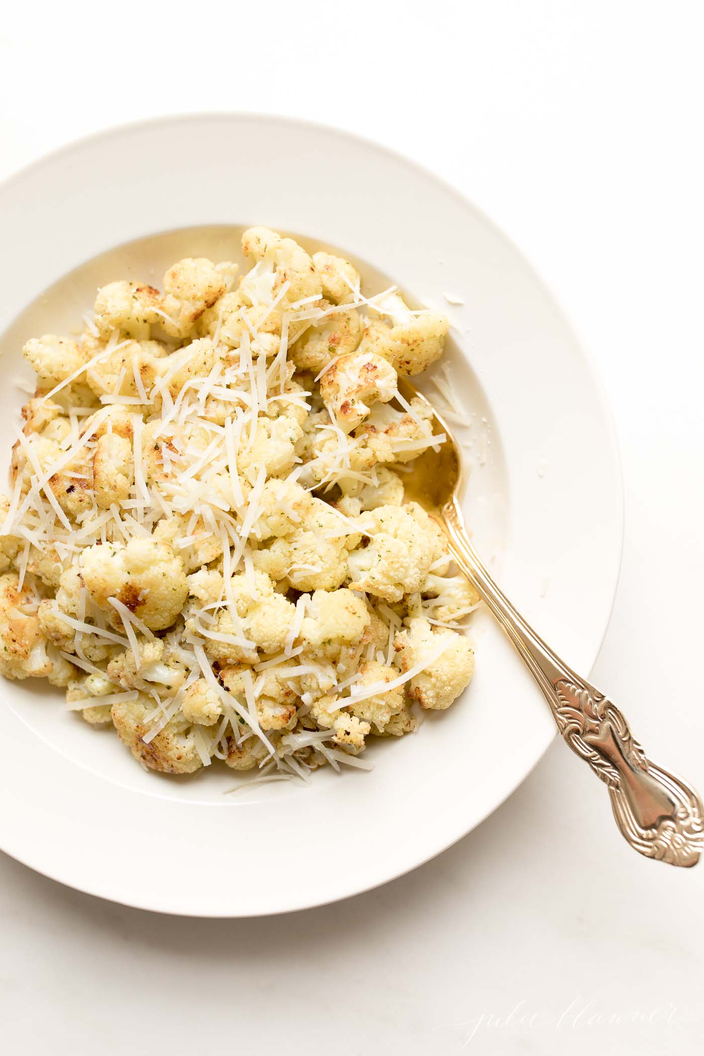 A white plate full of roasted cauliflower, gold spoon to the side, as a meatloaf side 