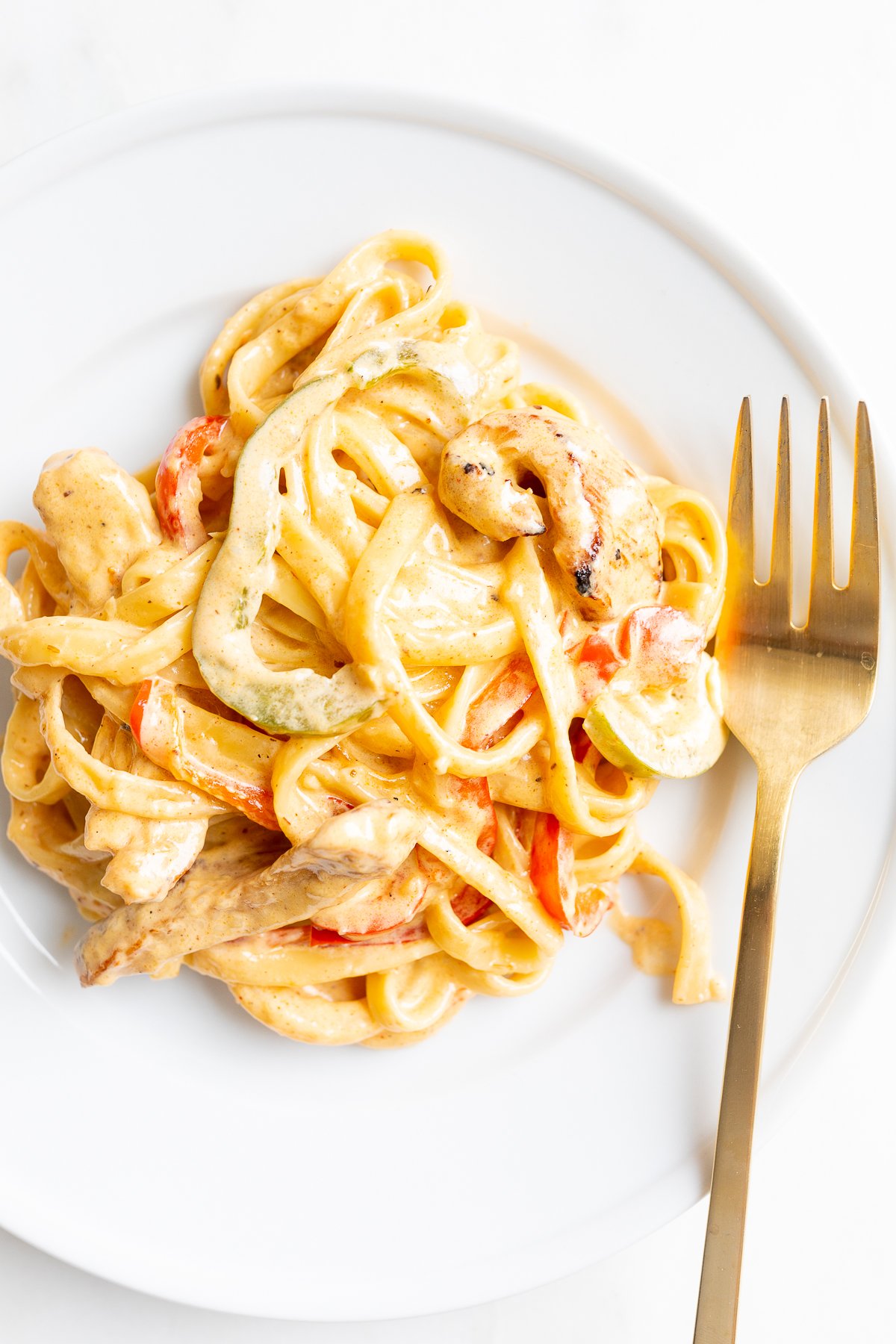 A white plate with a serving of Cajun chicken pasta.