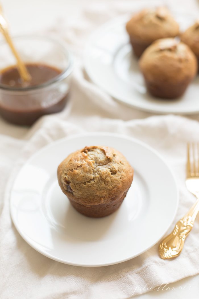 Caramel and Banana Muffin on a white plate, gold silverware to the side.