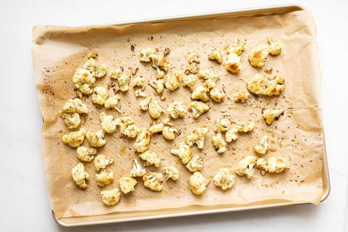 Roasted cauliflower on a parchment lined baking sheet.
