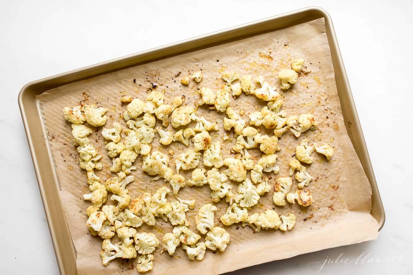 roasted cauliflower on a gold baking sheet in a burger sides round up post