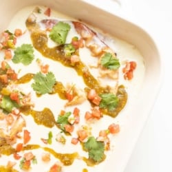 a mexican breakfast casserole covered in white queso and toppings in a white baking dish