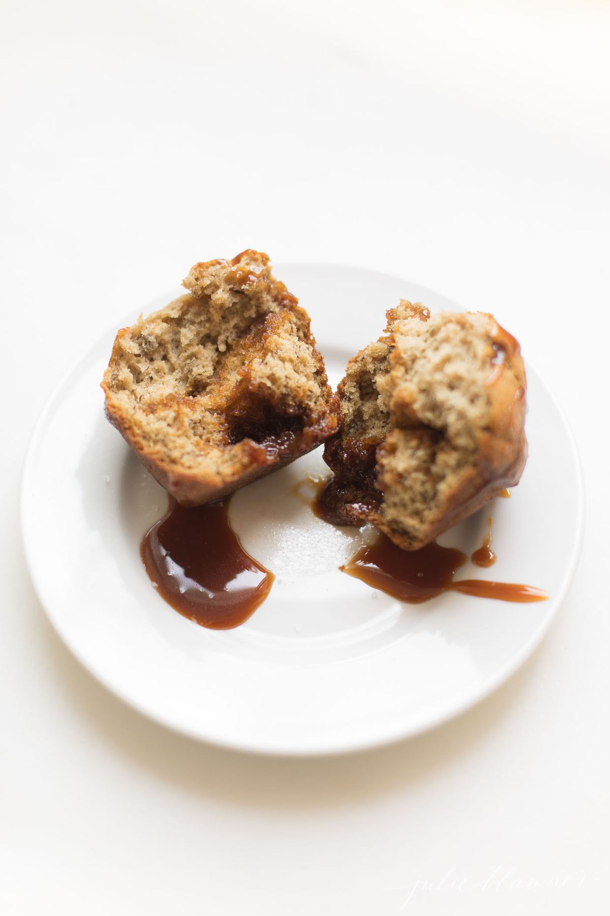 Caramel and Banana Muffin split in half on a white plate.