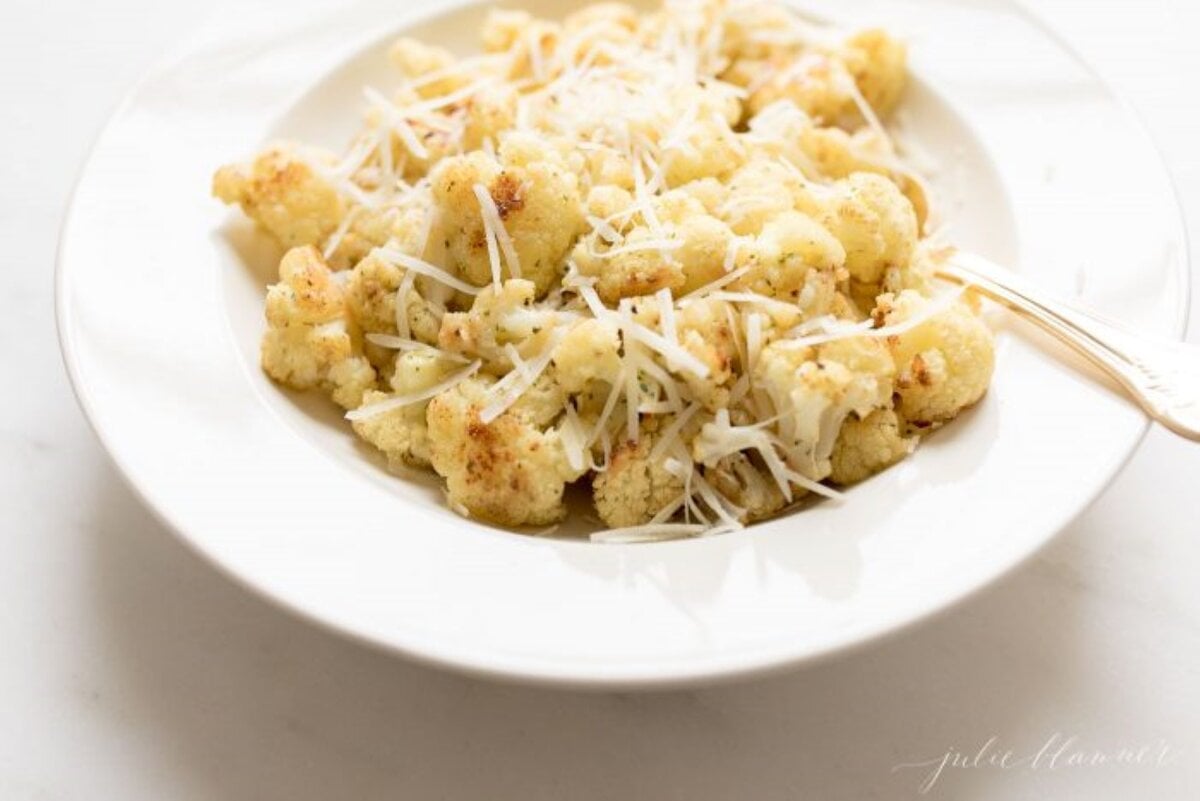 fiesta ranch roasted cauliflower on a white plate, topped with grated parmesan cheese.