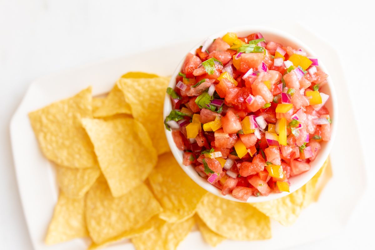 A platter of tortilla chips with a bowl of fresh watermelon salsa.