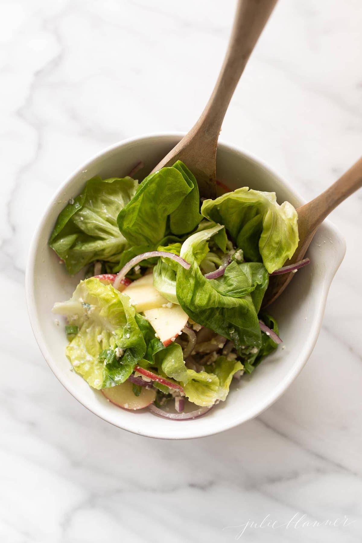 Apple Salad in a white bowl with wooden serving spoons