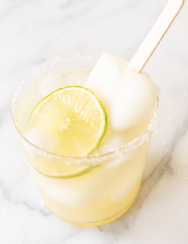 A Lime Popsicle Margarita in a glass on a marble surface.