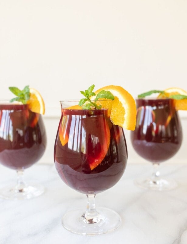 Three cups of sangria, garnished with a lemon slice and mint.