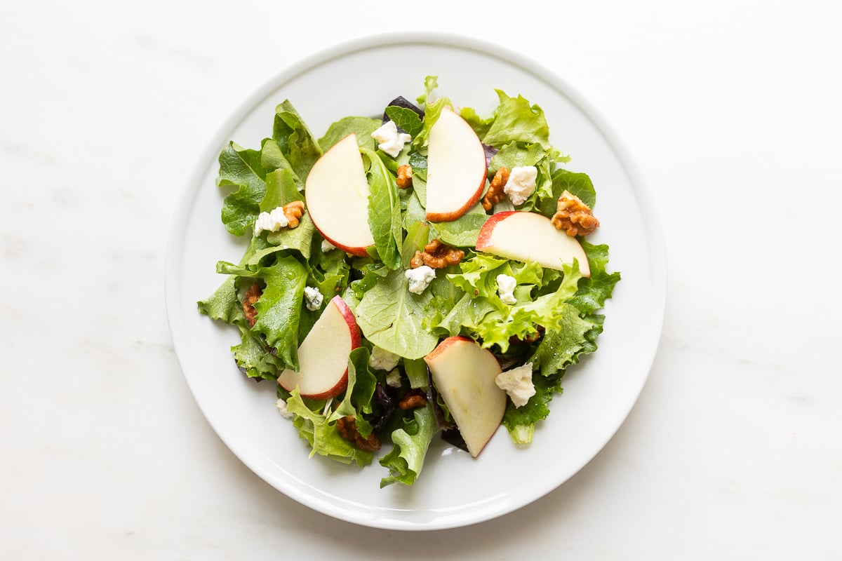 A white plate filled with an apple salad.