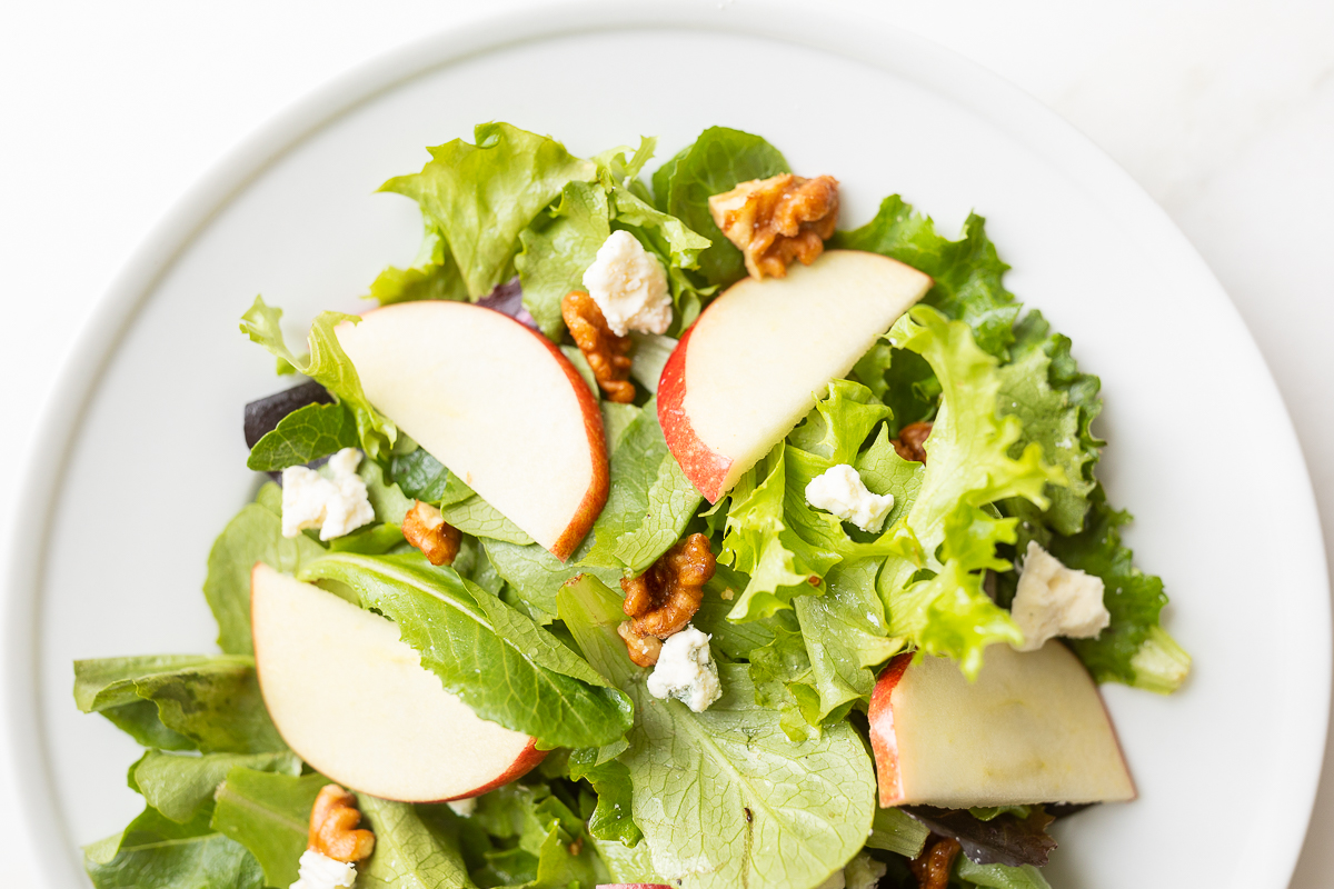 A white plate filled with an apple salad.