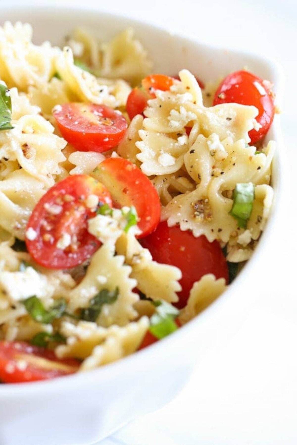 A bowl of easy pasta salad with cherry tomatoes and herbs.
