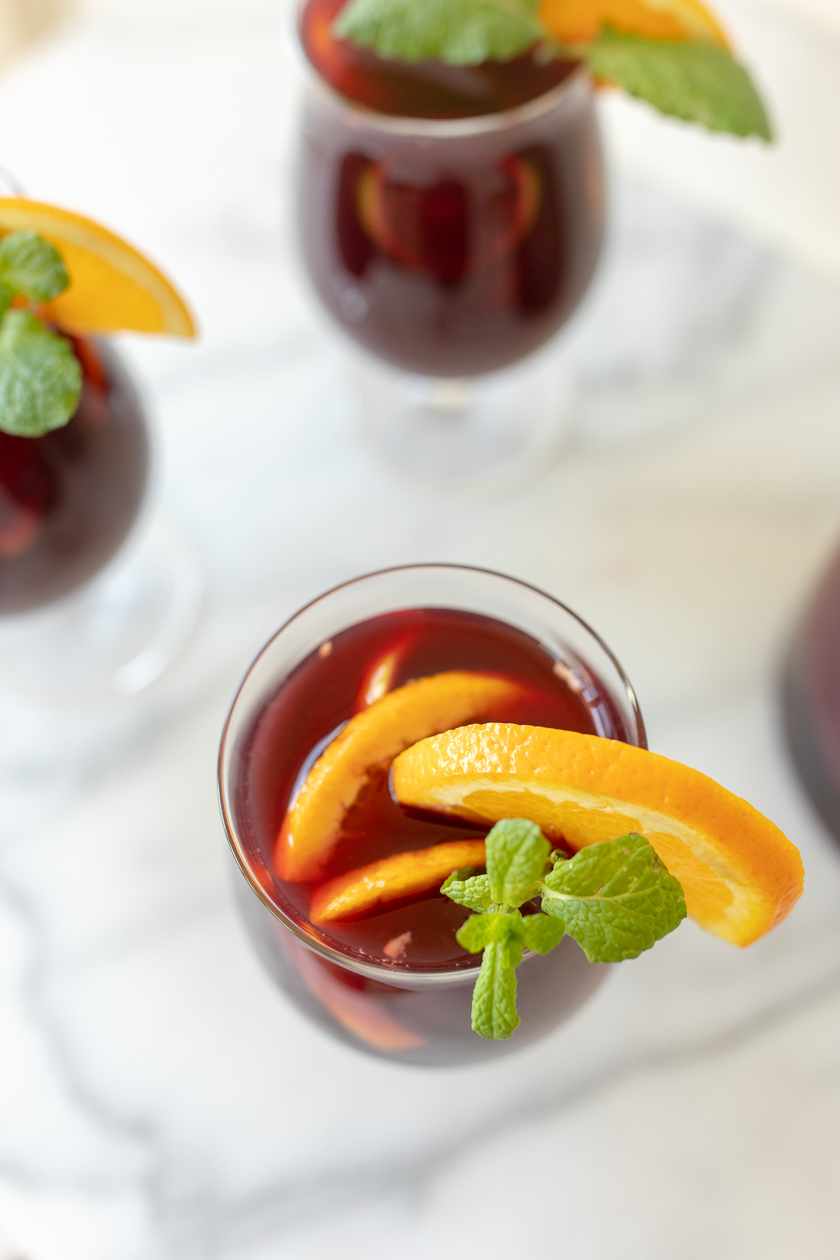 Traditional red sangria in stemware, garnished with fresh mint and orange slices.