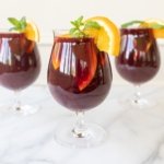 Traditional red sangria in stemware, garnished with fresh mint and orange slices.