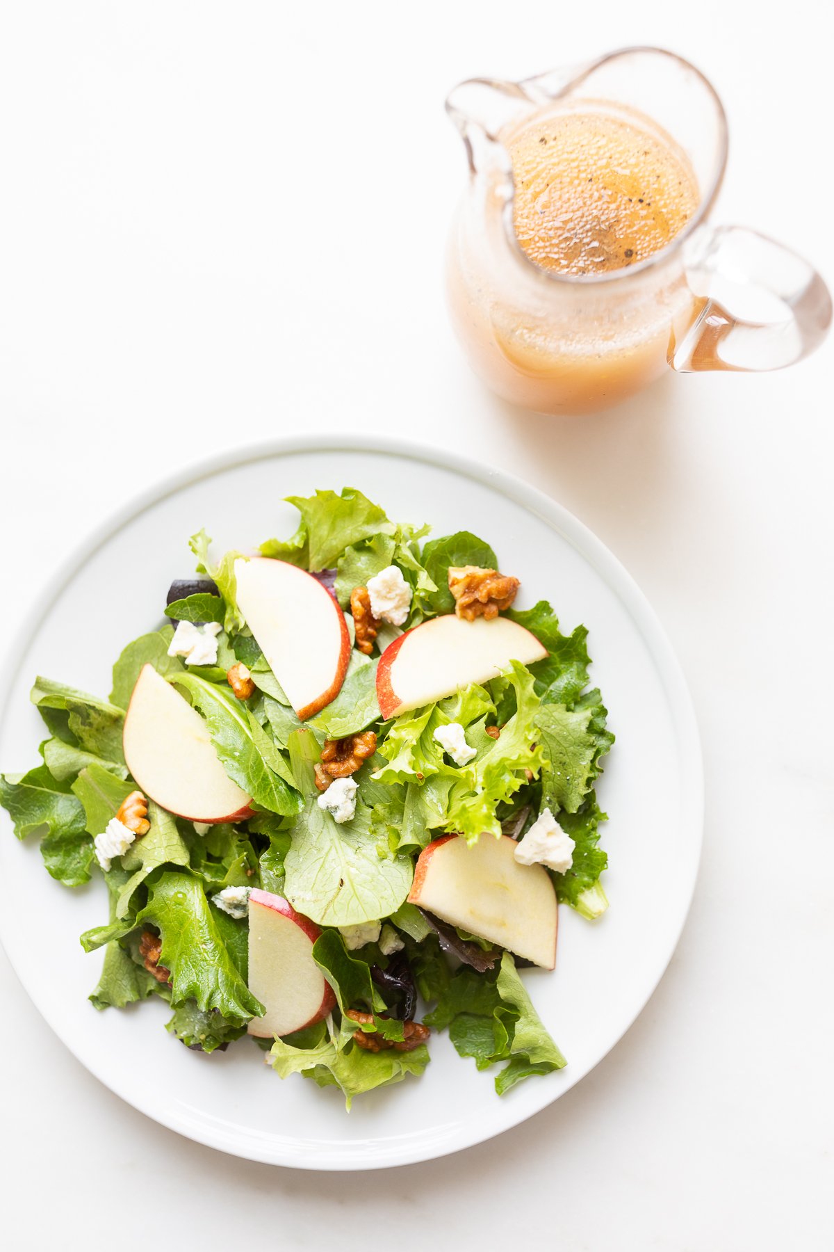 A white plate filled with an apple salad.