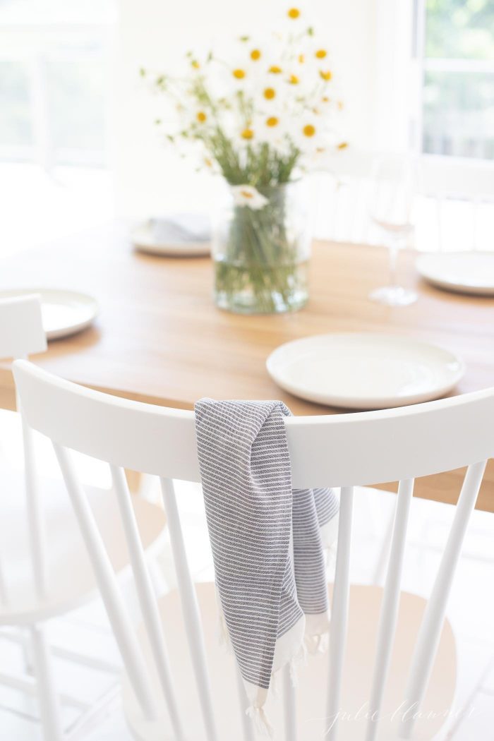 white dining chairs at small dining table with flowers