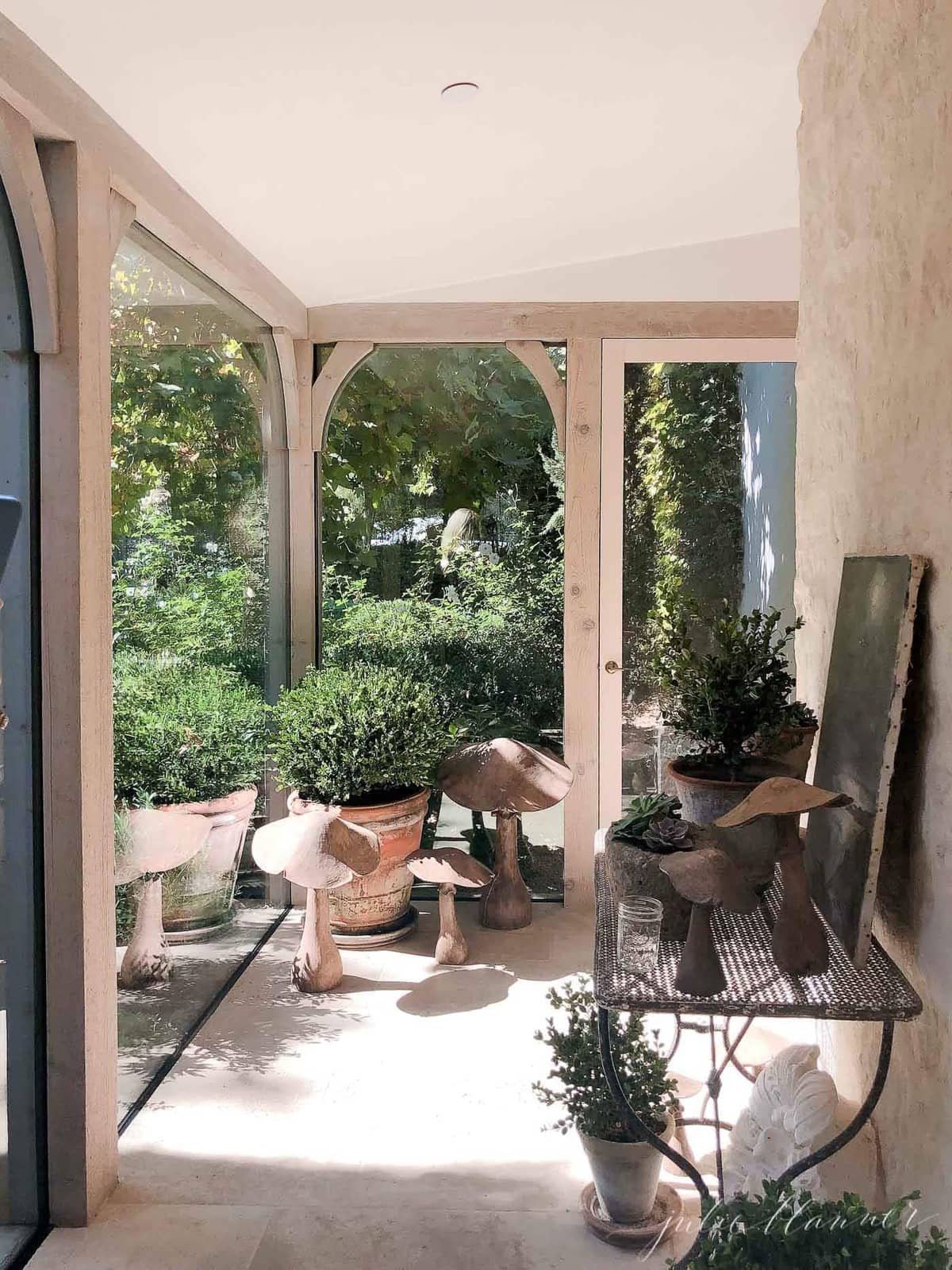 French country farmhouse patio with plants and mushroom statuary.