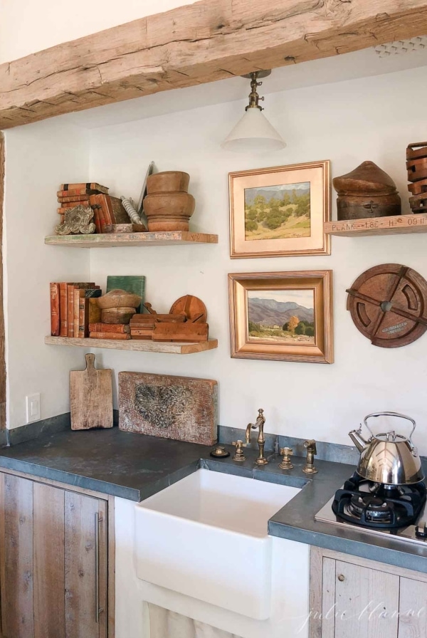 pottery on shelves with art wood beams soapstone counters and farmhouse sink