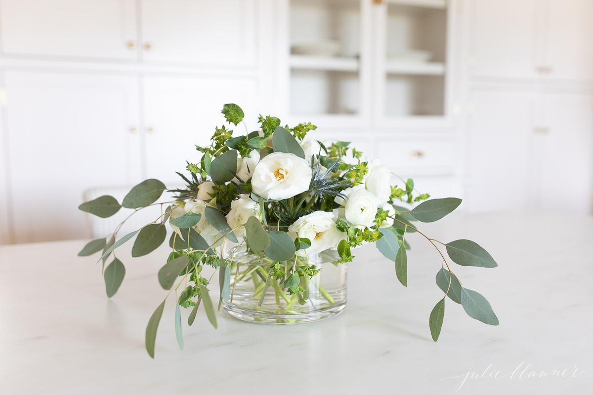 Flowers in a glass vase on a marble kitchen countertop. 