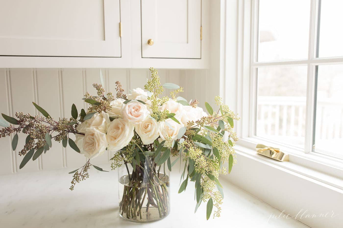 Roses in a glass vase on a white kitchen countertop. 