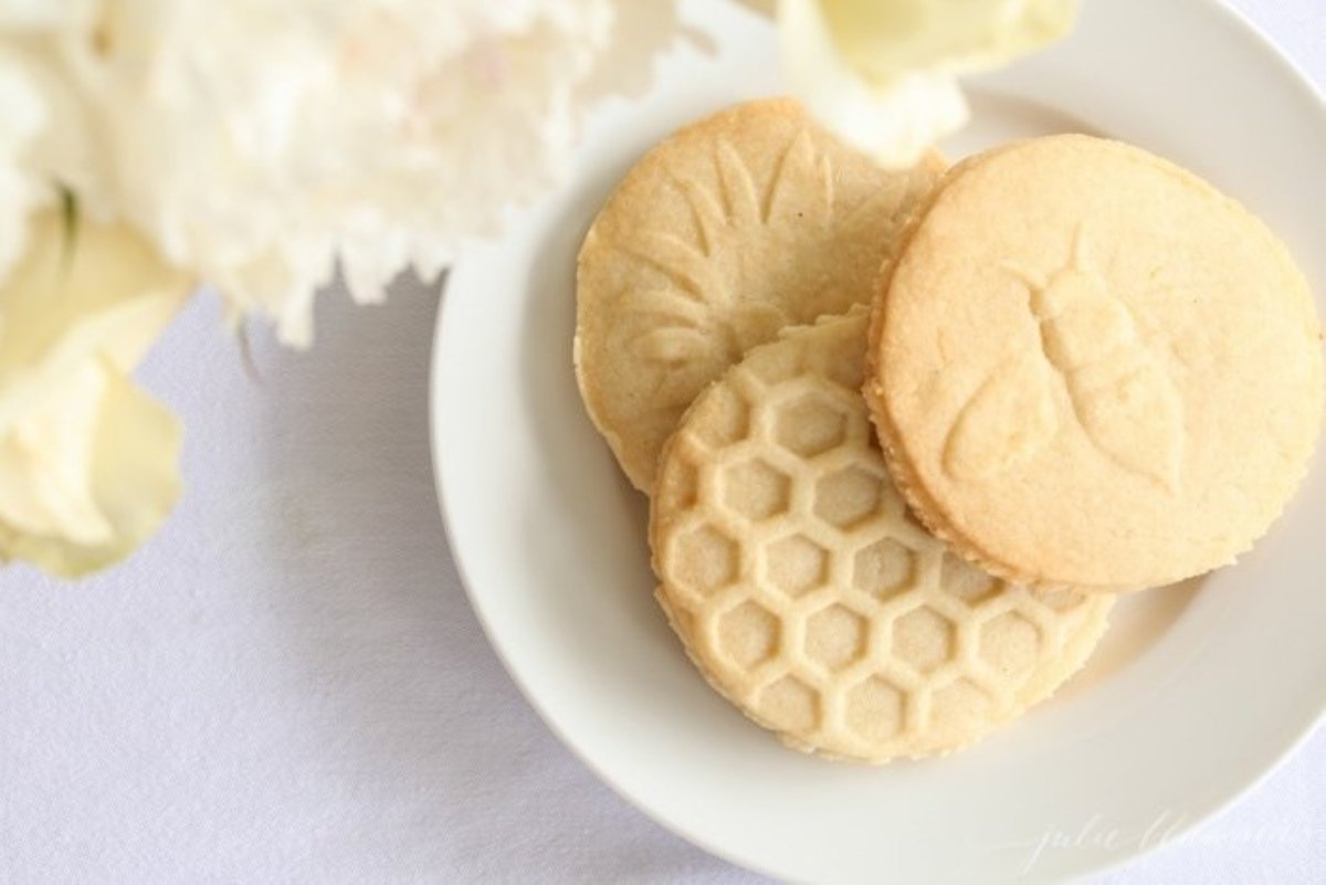 Lemon shortbread cookies on a white plate with fresh flowers nearby
