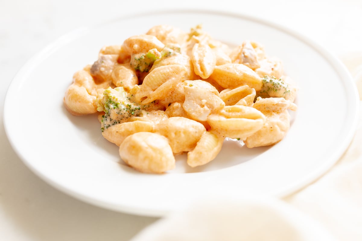 A white plate of pasta con broccoli.