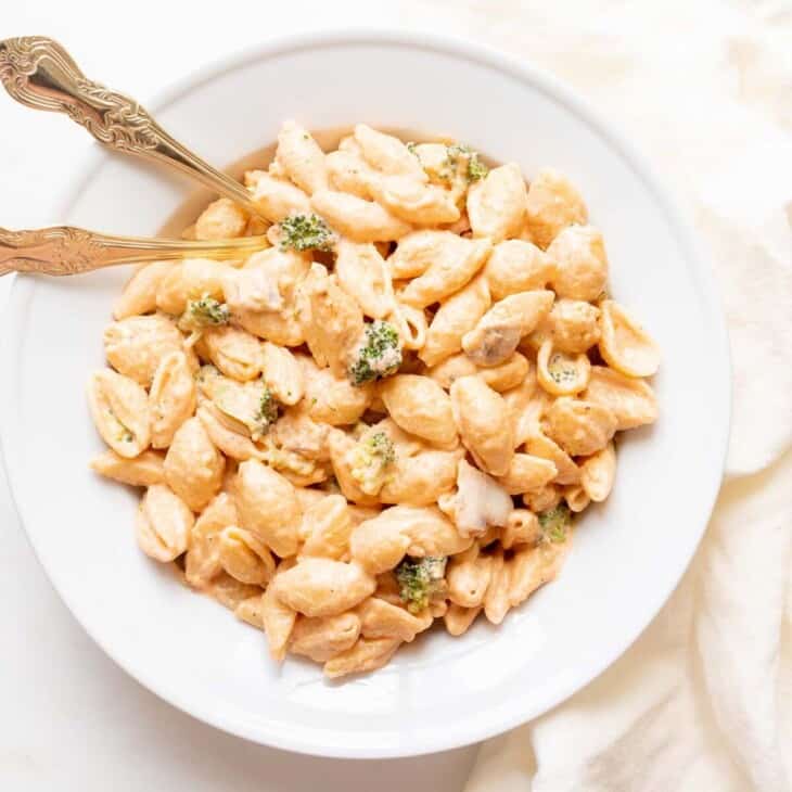 pasta con broccoli in white pasta dish with gold fork