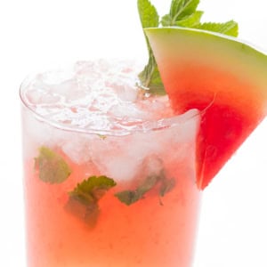 A refreshing watermelon mojito garnished with a slice of watermelon and fresh mint leaves in a clear glass.