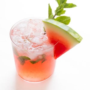 A refreshing watermelon mojito garnished with a slice of watermelon and fresh mint leaves in a clear glass.
