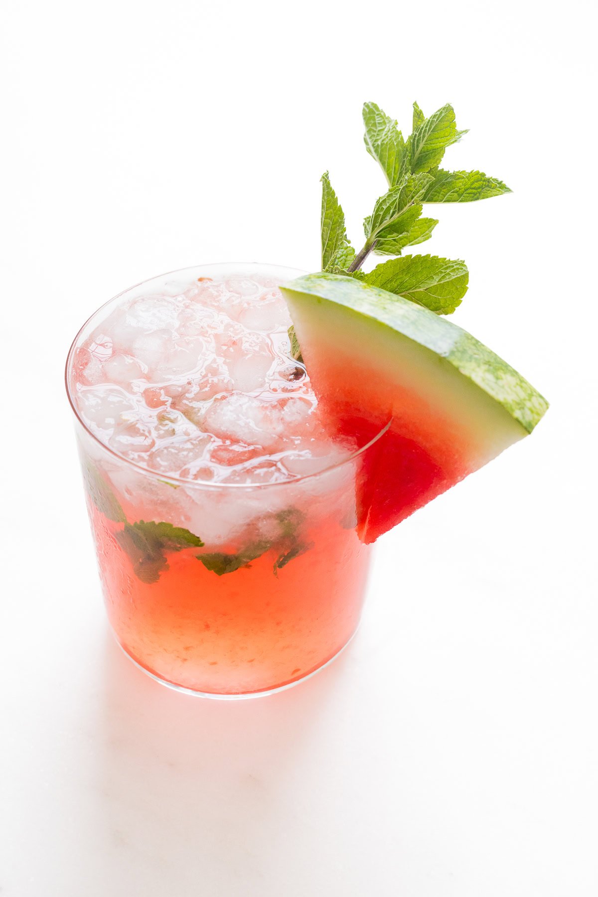 A refreshing watermelon mojito garnished with a slice of watermelon and fresh mint leaves in a clear glass.