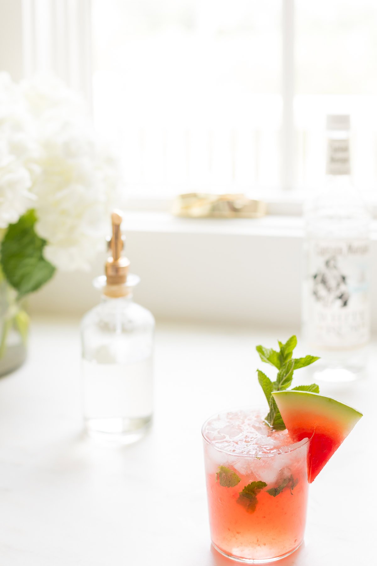 A refreshing watermelon mojito garnished with a slice of watermelon and fresh mint leaves in a clear glass.