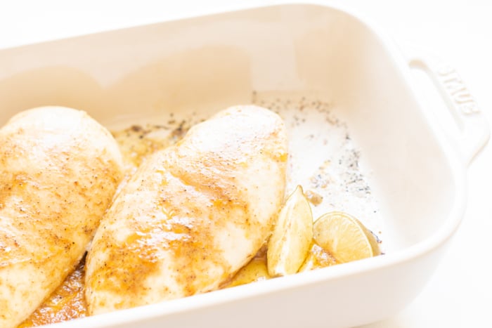 Baked chicken breasts in a white baking dish.