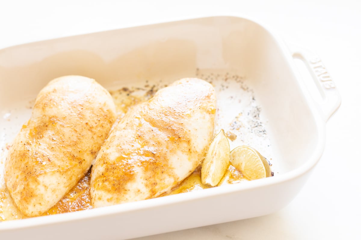Baked chicken breasts in a white baking dish.