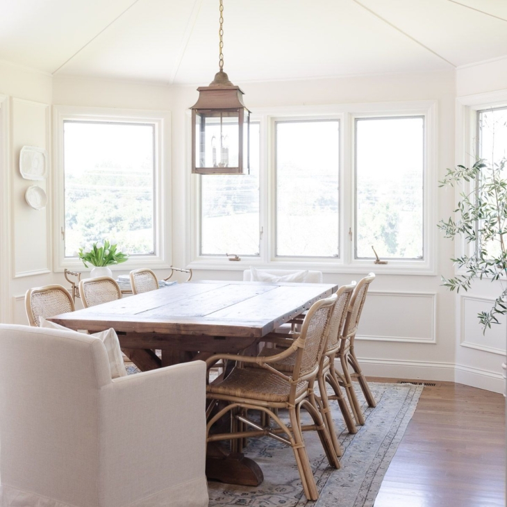 A casual dining room with cream walls and a cream color ceiling, with a wood dining table.