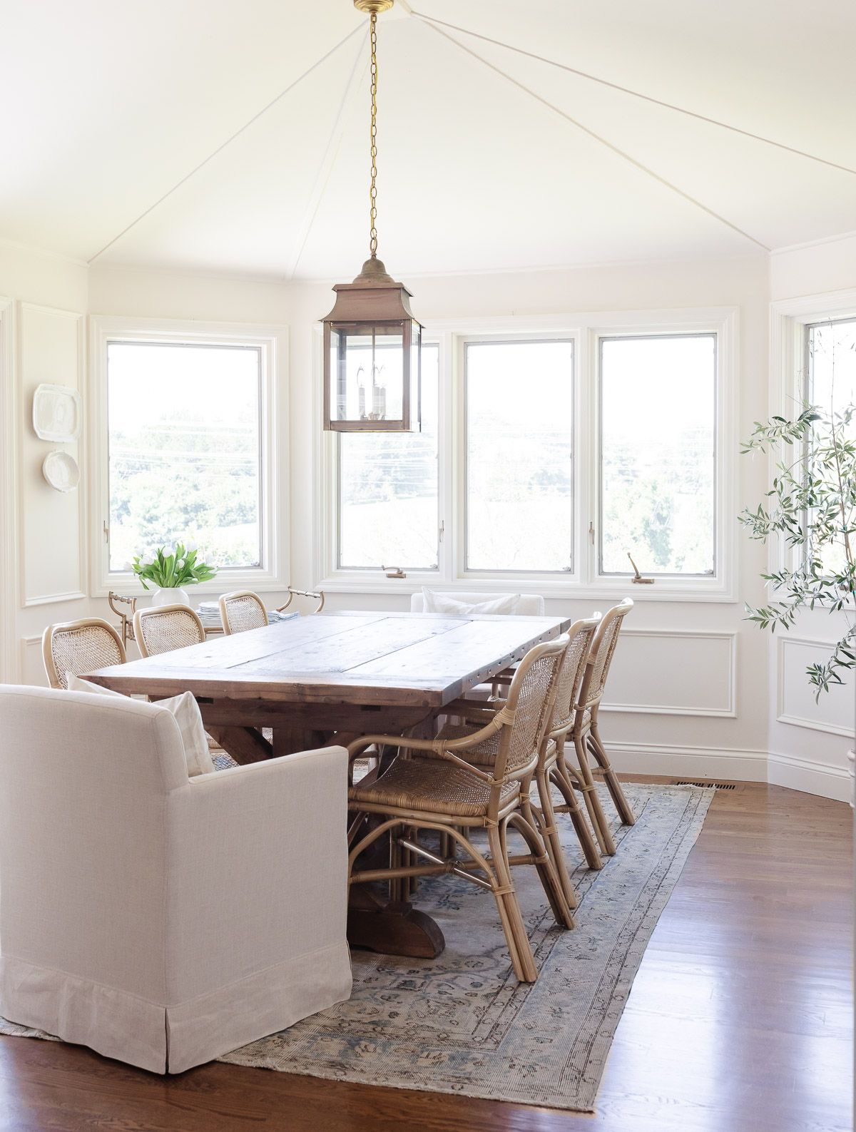 A casual dining room with cream walls and a cream color ceiling, with a wood dining table.